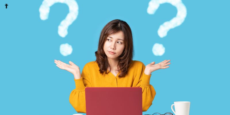 A woman sits in front of a red laptop with a confused expression, shrugging her shoulders. There are two large question marks in white cloud shapes on either side of her head, hinting at possible amateur blogging mistakes. She is wearing a yellow sweater, and a white cup is on the desk beside her.