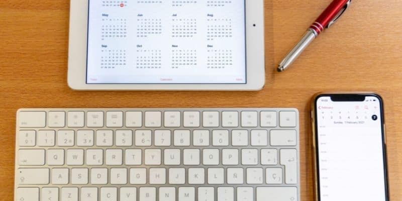 computer keyboard, pen, smartphone, and tablet with calendar