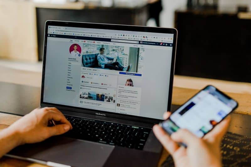 Man updating facebook page on laptop