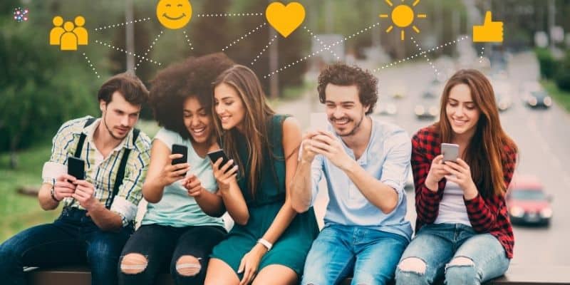 A group of five young adults sit outdoors, smiling and looking at their smartphones. Above them are various icons, including a heart, a smiley face, a sun, and a thumbs-up, connected by dotted lines. These symbols represent the diverse social media content buckets they engage with daily.