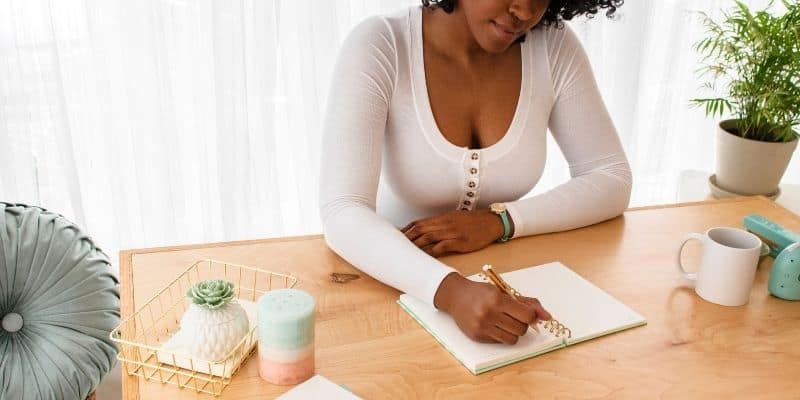 Woman doing business writing about her client avatar in a notebook