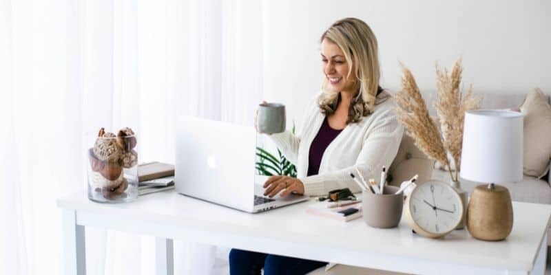 Woman doing business writing on laptop with gray mug