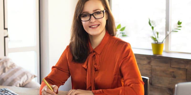 Woman in burnt orange shirt and dark glasses creating her freelance business name