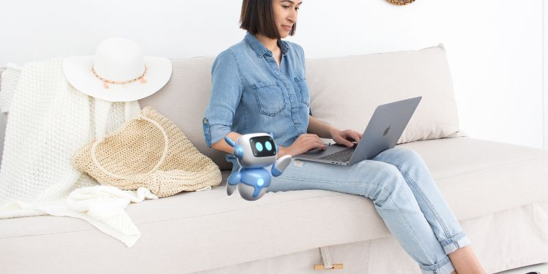 A woman in a denim outfit sits on a beige sofa using a laptop, exploring ChatGPT prompts for content writing. A white hat and woven bag rest nearby, while a small, cartoonish robot with glowing blue features is beside her.