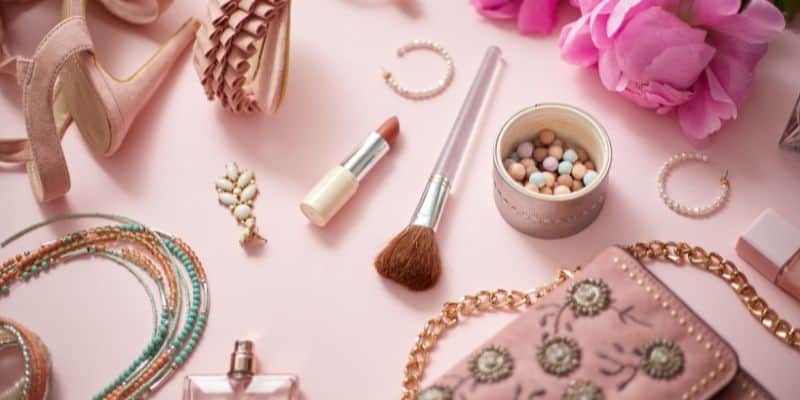 beauty products and make up accessories on a pale pink background