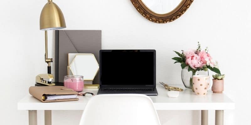 desk with blush accents and neutral colored folders and laptop writer uses