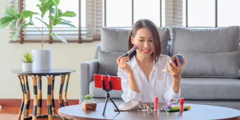 A woman is sitting on a couch, brainstorming fall content ideas while holding a cell phone.