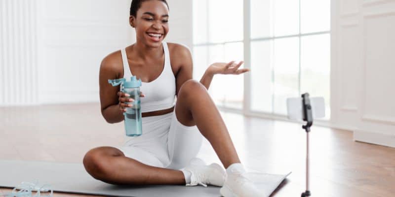 A woman on a yoga mat with a water bottle, capturing fall content ideas.