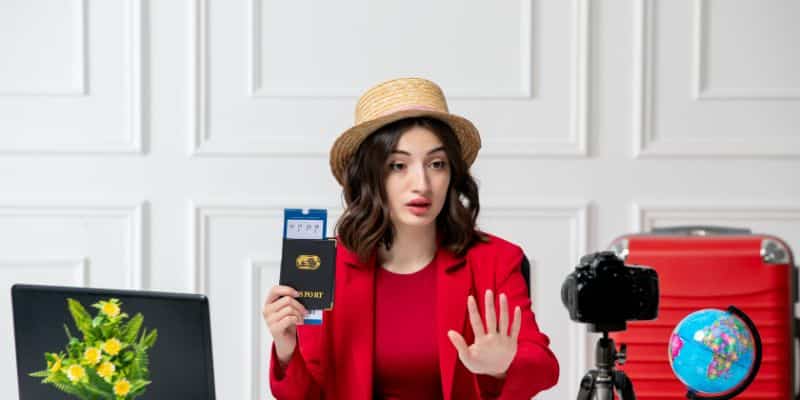 A woman in red researching fall content ideas on her laptop with a passport by her side.