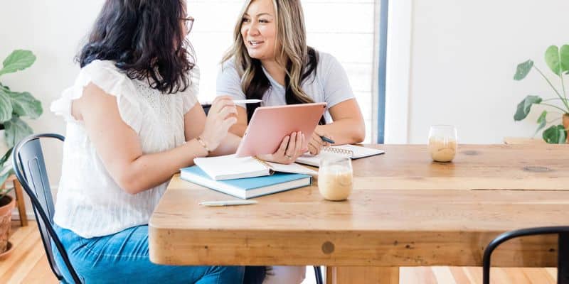 freelance writer and client talking over her tablet with notebooks