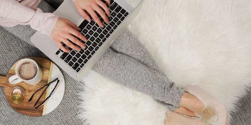 freelance writer working from home on a white furry blanket in her pajamas