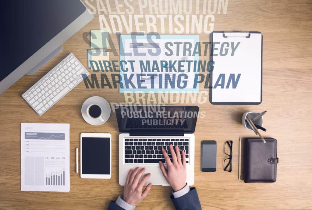 man on a laptop with marketing plan, advertising, and other sales terms