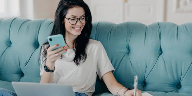 freelance writing niches woman on a blue sofa writing copy on a laptop