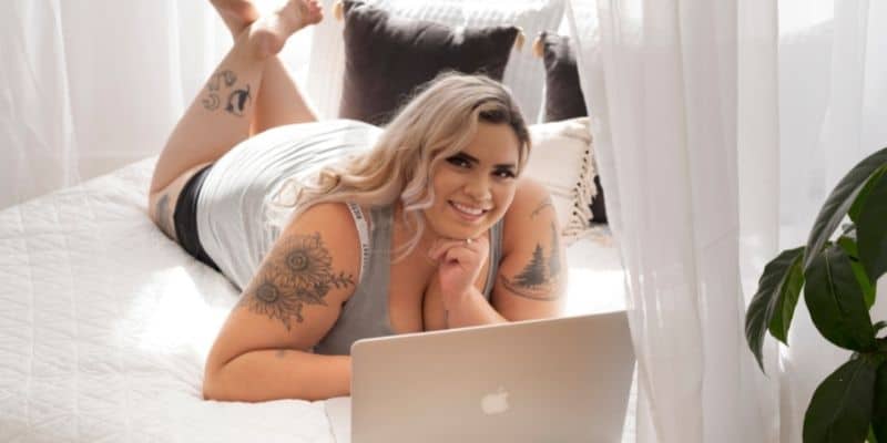 freelance writing resume woman with tattoos on a bed with laptop