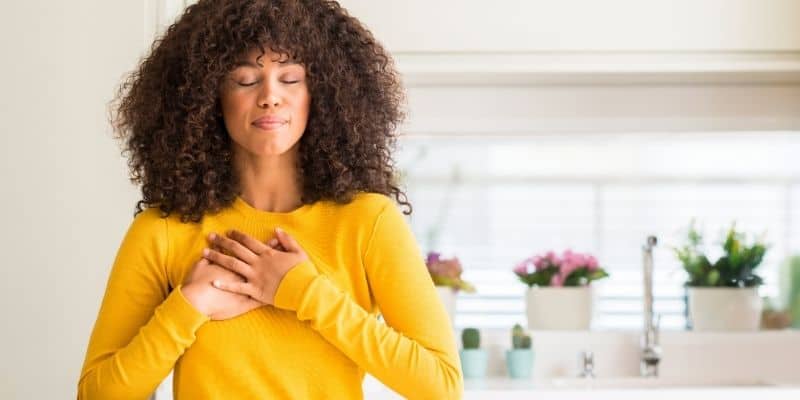 grateful mindset mastering your mindset woman with curly hair in a yellow shirt with hands crossed on chest