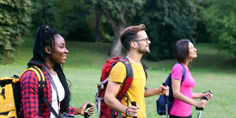 A group of people walking with backpacks in a park, demonstrating how to maintain a work-life balance.