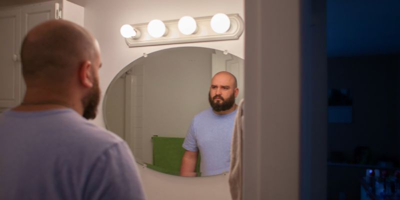 imposter syndrome journal prompts man staring at his reflection feeling like an imposter