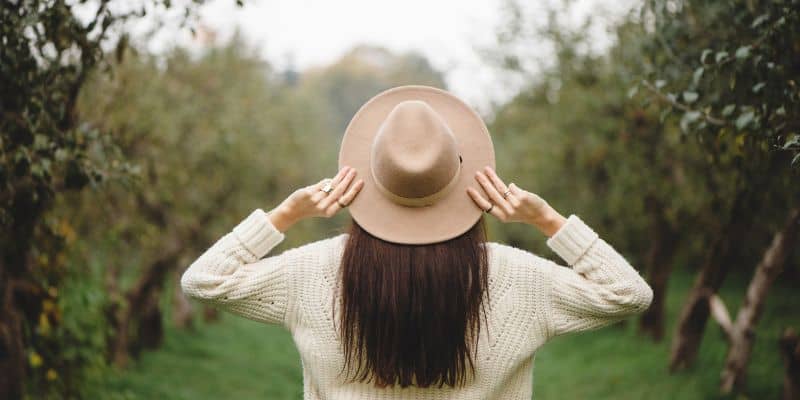 lifestyle blogger with a beige hat and cream sweater in a vineyard