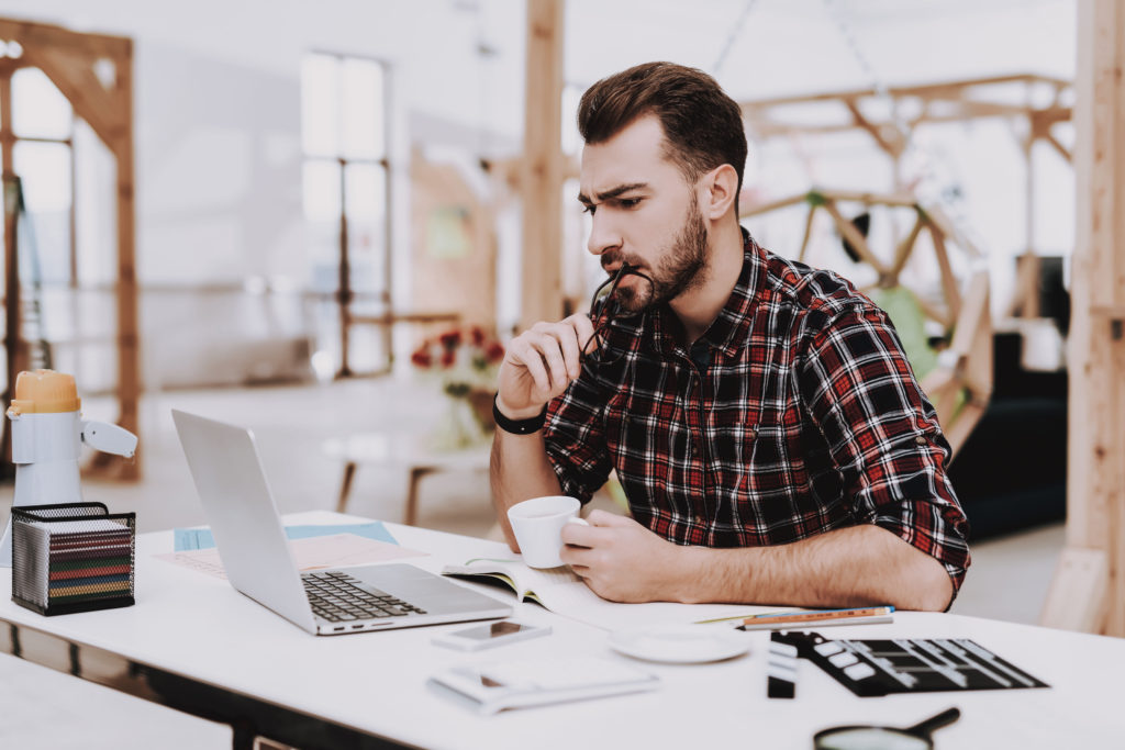 man at desk with laptop and coffee