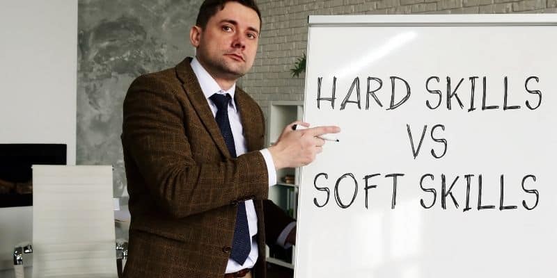 man in brown jacket with paper that says hard skills vs soft skills