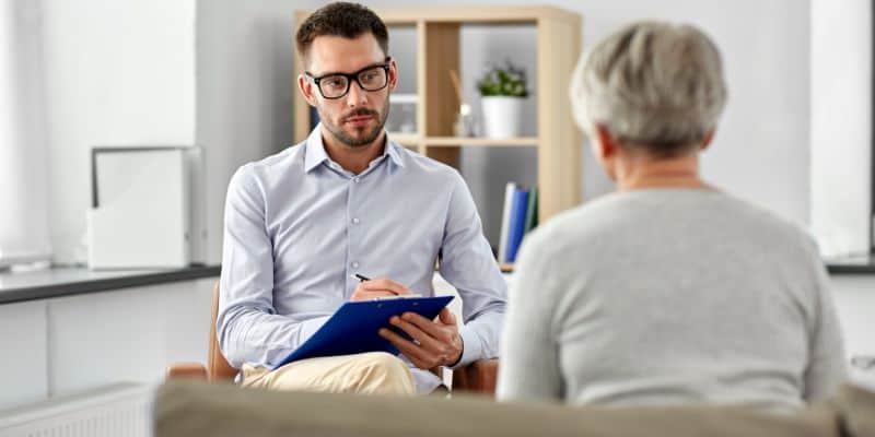 psychologist with a clipboard counseling a patient