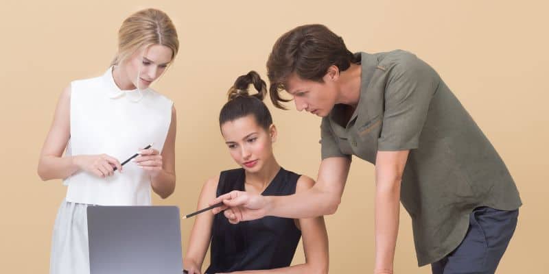 three people working over a laptop giving feedback on a freelance business name