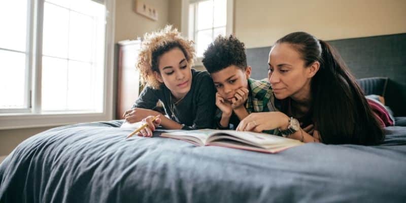 two women helping a young boy study