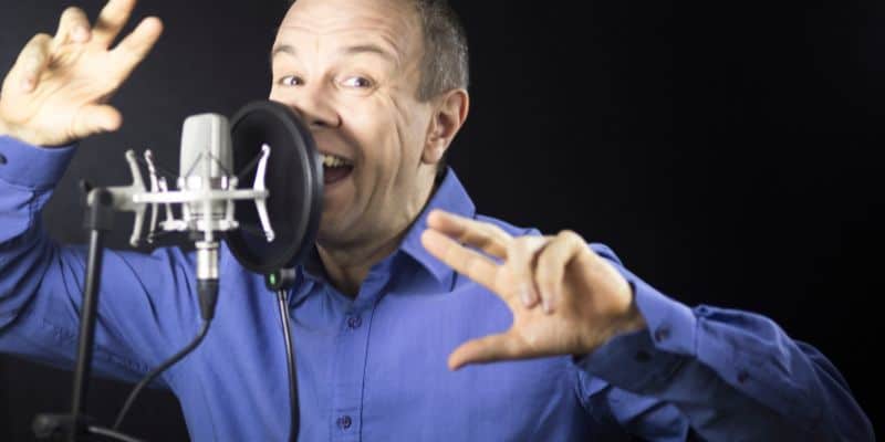 voice over artist in a blue shirt talking into a microphone