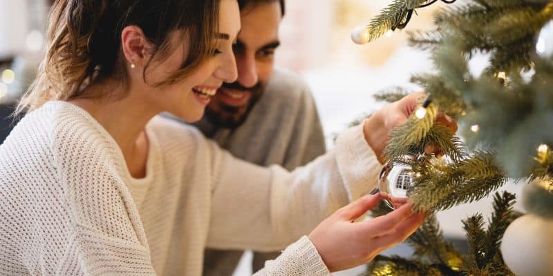 woman and man adding Christmas ornaments on a Christmas tree (1)