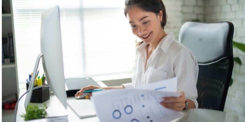 woman at computer desk with papers smiling