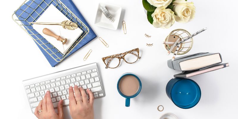 woman creating her content typing on a keyboard with other desk accessories