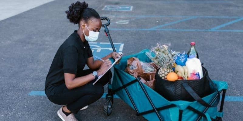 woman wearing black delivering groceries in a cart