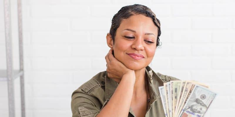 woman in a green shirt counting money in various denominations