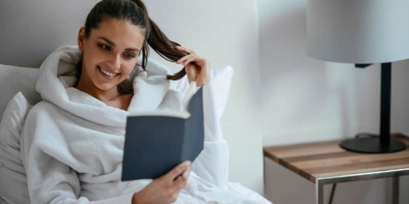 woman in bathrobe reading book