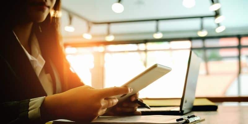 woman looking at phone by computer