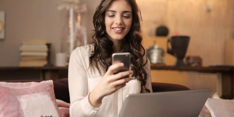 woman looking at phone by the computer