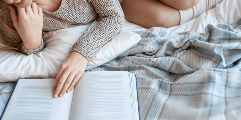 woman on bed smiling reading book