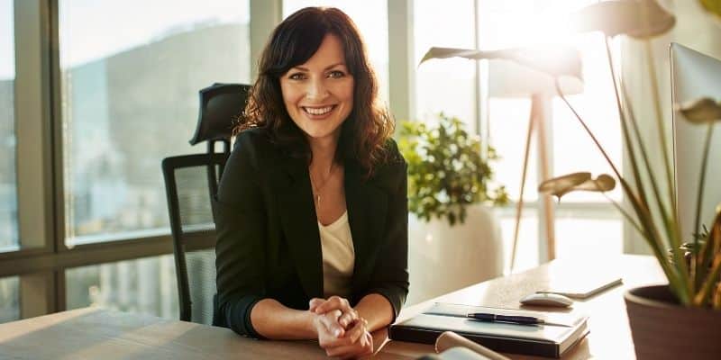 woman sitting at desk smiling at camera