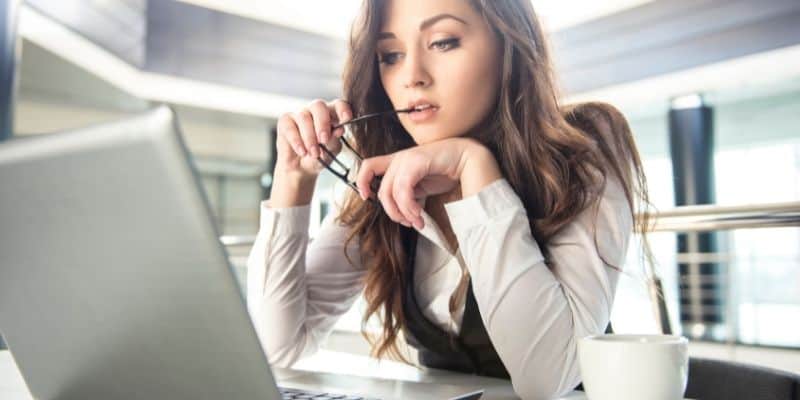 woman with glasses in hand on computer