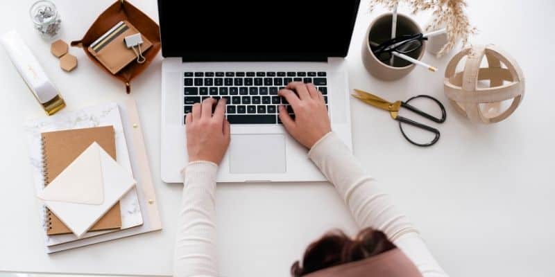 woman working on virtual assistant work on laptop with light brown accents