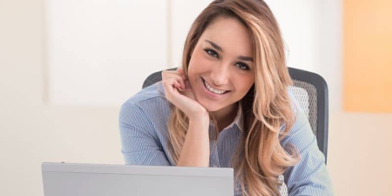 woman in blue shirt smiling at camera by computer